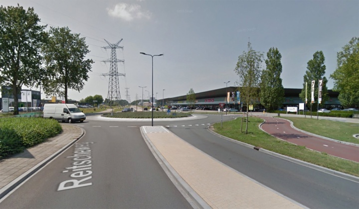The connection Reitscheweg - Aziëlaan has become a roundabout for motor traffic that is by-passed by a bi-directional cycleway. A re-located parking-lot access makes it a four-arm roundabout where there was only a T-junction before.
