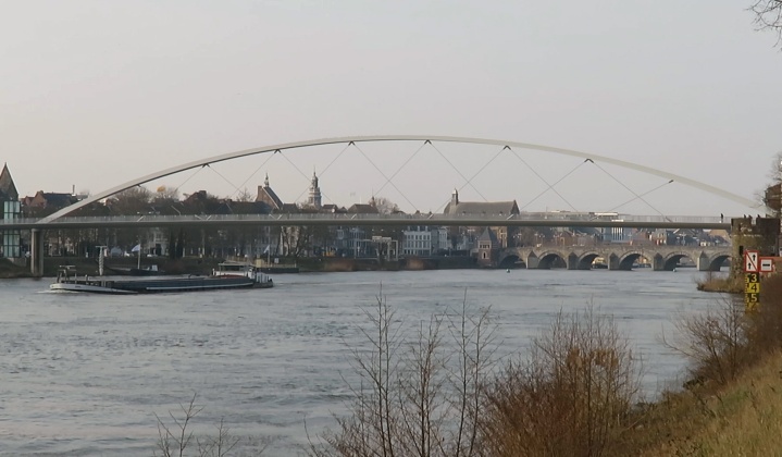 The arch of the cycle bridge over the Meuse river. In the distance the old bridge. A bridge was first built by the Romans, but this version dates back to the 13th century.